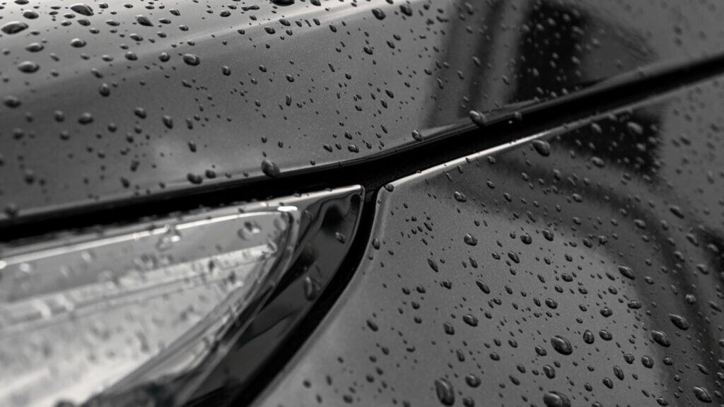 Water droplets beading on a protected black car panel