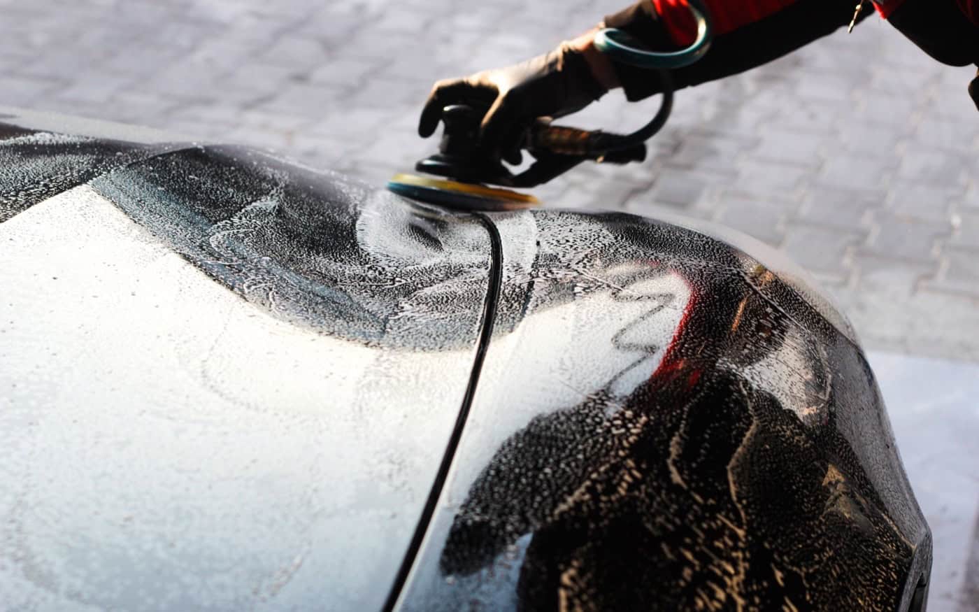 Detailer preparing a car panel with a polishing machine